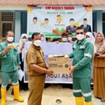 Rafiq Adriansyah selaku Head of Field Support dan Supriadi selaku Public & Government Relation Kingswood Capital Ltd. Menyerahkan masker kepada Irianto selaku Kepala Sekolah SMPN 5 Tandun