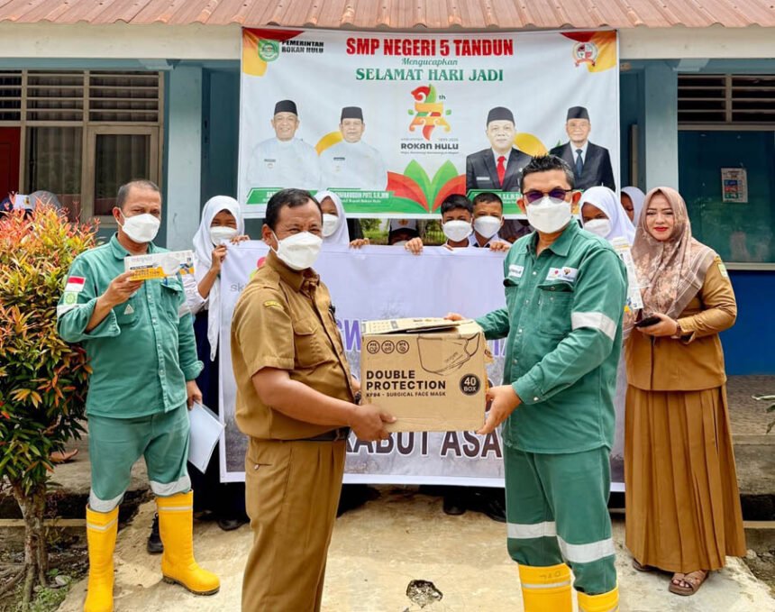 Rafiq Adriansyah selaku Head of Field Support dan Supriadi selaku Public & Government Relation Kingswood Capital Ltd. Menyerahkan masker kepada Irianto selaku Kepala Sekolah SMPN 5 Tandun
